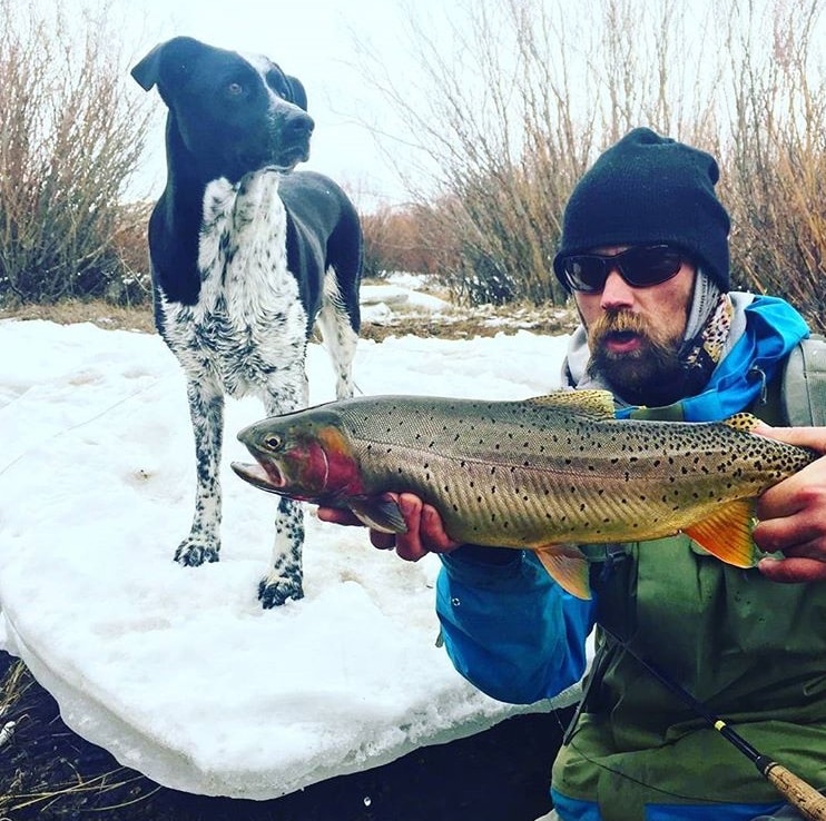 Dan Greene, with his dog Roy, holds a cutthroat trout caught in southwest Montana. © Jeremy Clark