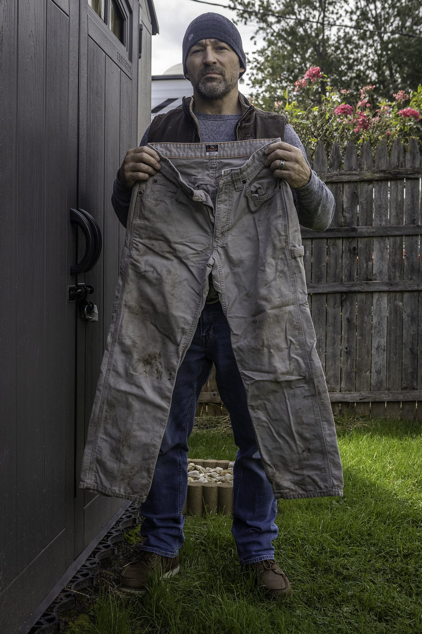 Eric Seppe in the backyard of his home holding the soiled work pants he wore on the day of the accident. (Note: the work pants were washed after the accident) © Steven Rubin for Public Herald